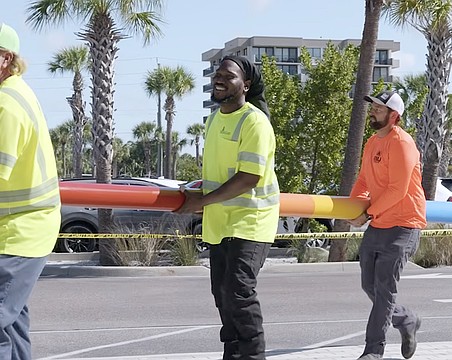 Workers carry one of two storm surge poles Sarasota County has installed at Siesta Beach and Manasota Beach.