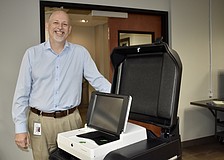 Supervisor of Elections Scott Farrington stands next to one of the new voting machines.