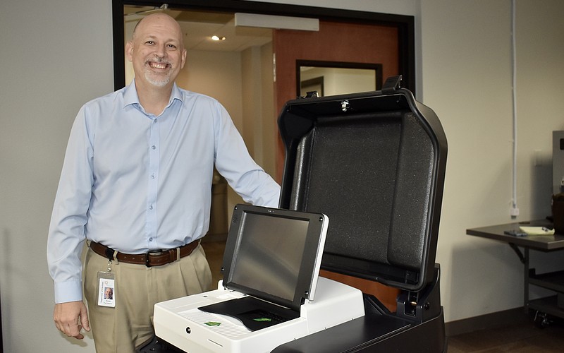 Supervisor of Elections Scott Farrington stands next to one of the new voting machines.
