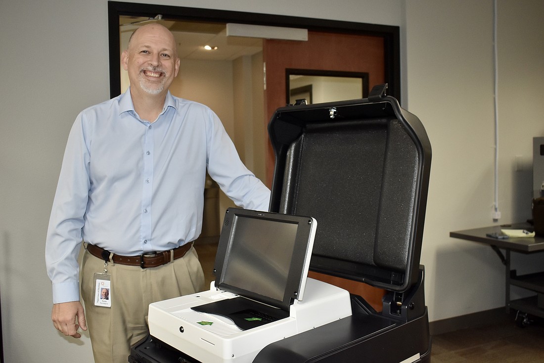 Supervisor of Elections Scott Farrington stands next to one of the new voting machines.