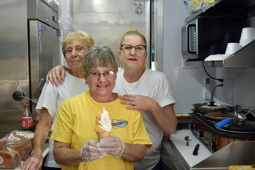 Longtime Mixon Fruit Farm employees Anita Stanley and Kaliah Muck stand behind Marie Lovy.