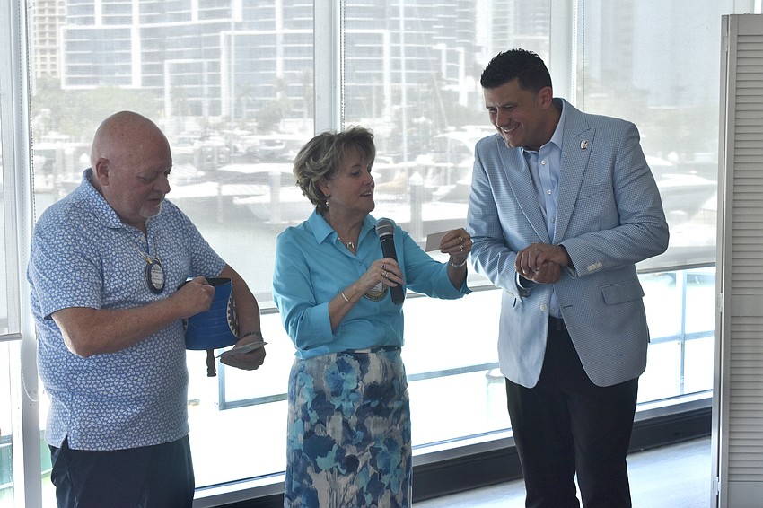 James Thompson and President Pam Akins work with Casey Gonzmart Jr. to draw prize tickets.