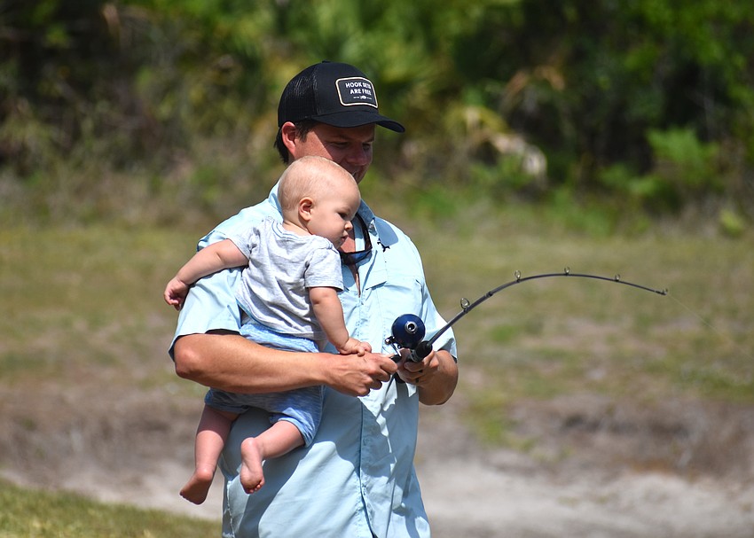Lakewood Ranch's Zack Barnett, with baby Renner in hand, helps retrieve the lure of older son Wiley at the Youth & Teen Fishing Seminar.