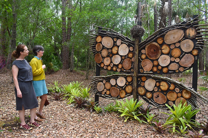 Eirinn Camphire and Tina Juillerat stop to admire a butterly made of wood on the Peaceful Path May 2.