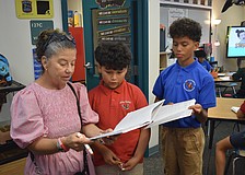 Tammy King talks with fourth graders Dylan Amador-Guerra and Knox Smith about their journals.