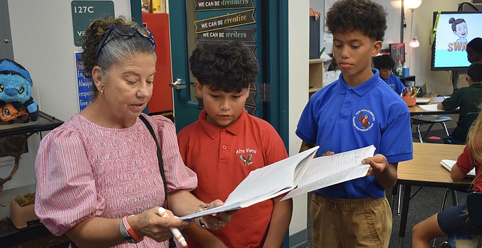 Tammy King talks with fourth graders Dylan Amador-Guerra and Knox Smith about their journals.