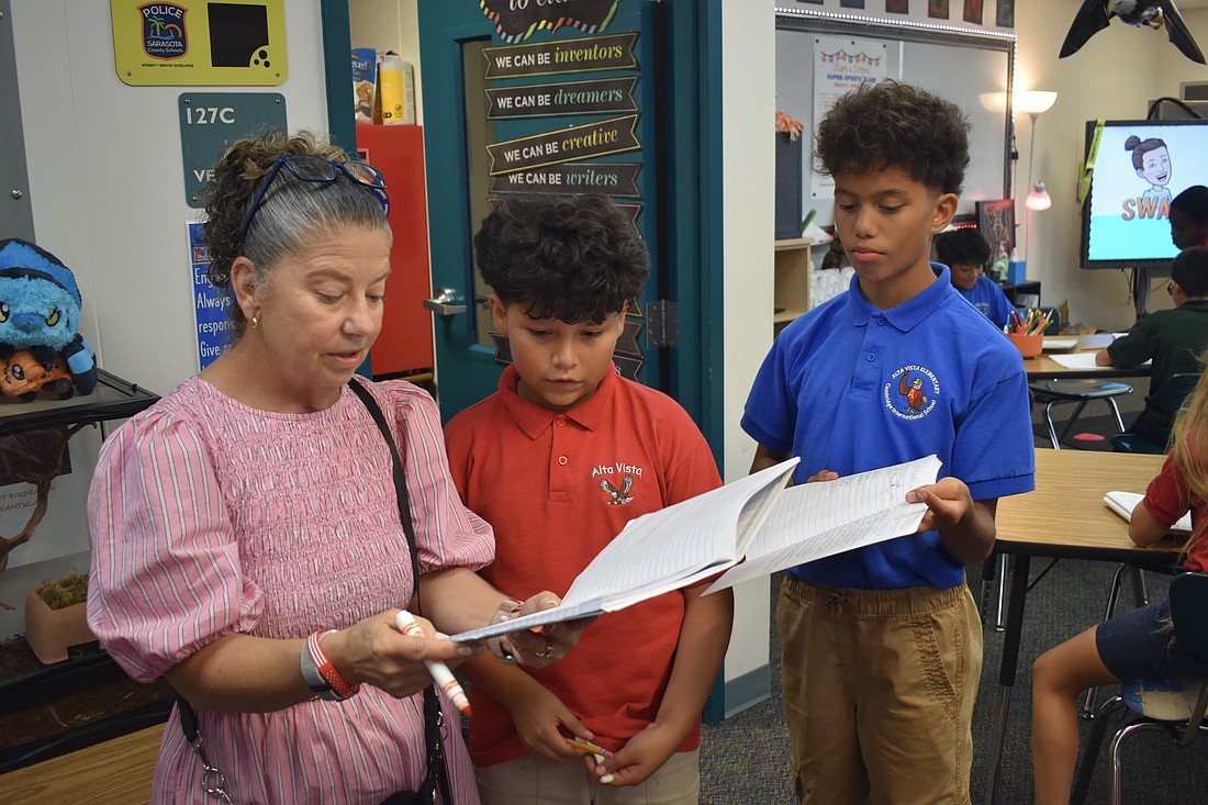 Tammy King talks with fourth graders Dylan Amador-Guerra and Knox Smith about their journals.