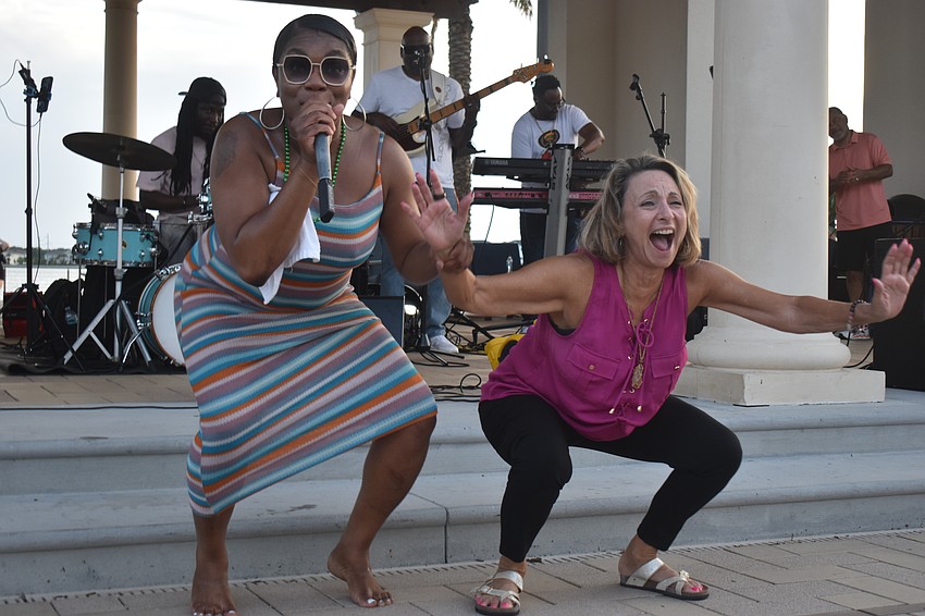 Shantel Norman, lead vocalist of Jah Movement, encourages Sarasota's Joy McGraw to dance in celebration of McGraw's 65th birthday.