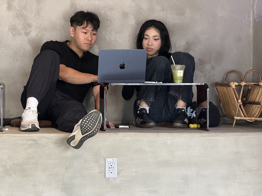 A couple collaborates on a project while sitting on the microcement bleachers at Cafecito.