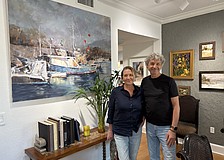 Marina and Vladislav Yeliseyev pose in front of one of Vlad's paintings in their home in The Landings.