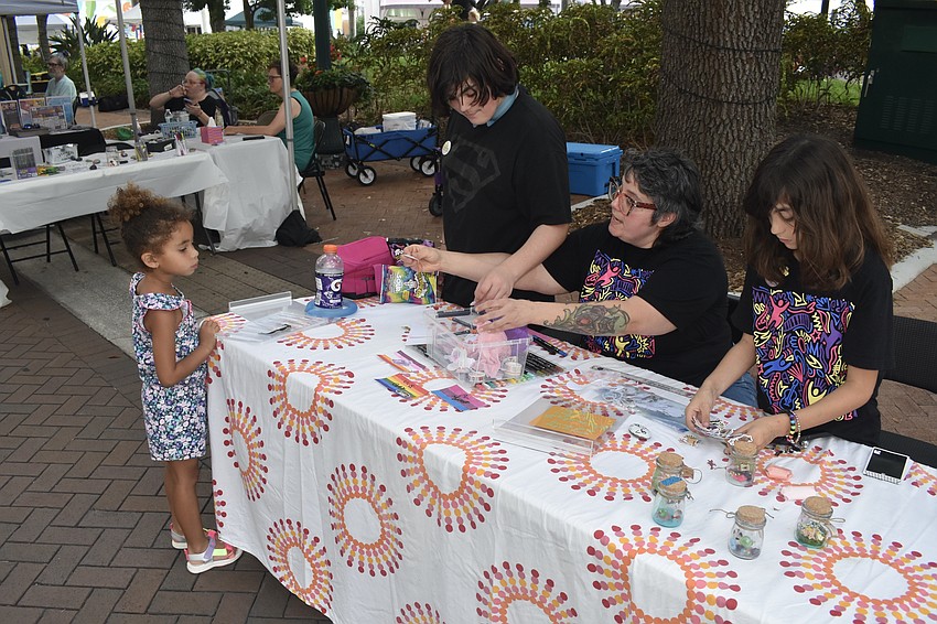 Maya Hunter-Ceruti, 5, visits the kids makers' table which is being staffed by Max Silvious, 13, his mother Heather Silvious and sister Tulip Silvious, 11.