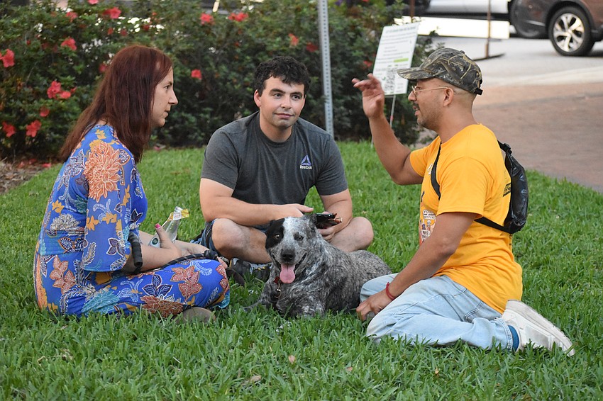 Friends Penny Leary, Luke Right and Carlos Valdez sit with Leary's dog Daisy in the park.