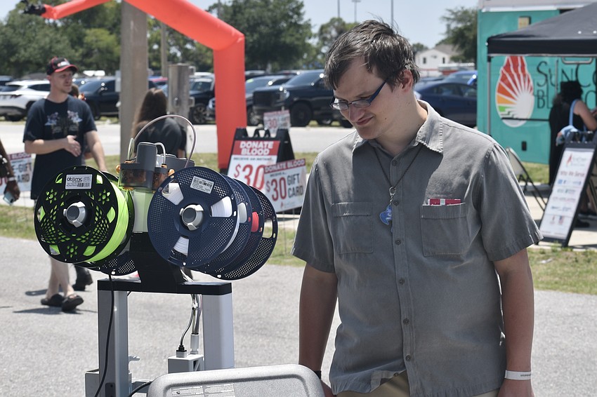 Cory Graff watches a 3D printer at work, at the D3D Creations tent.