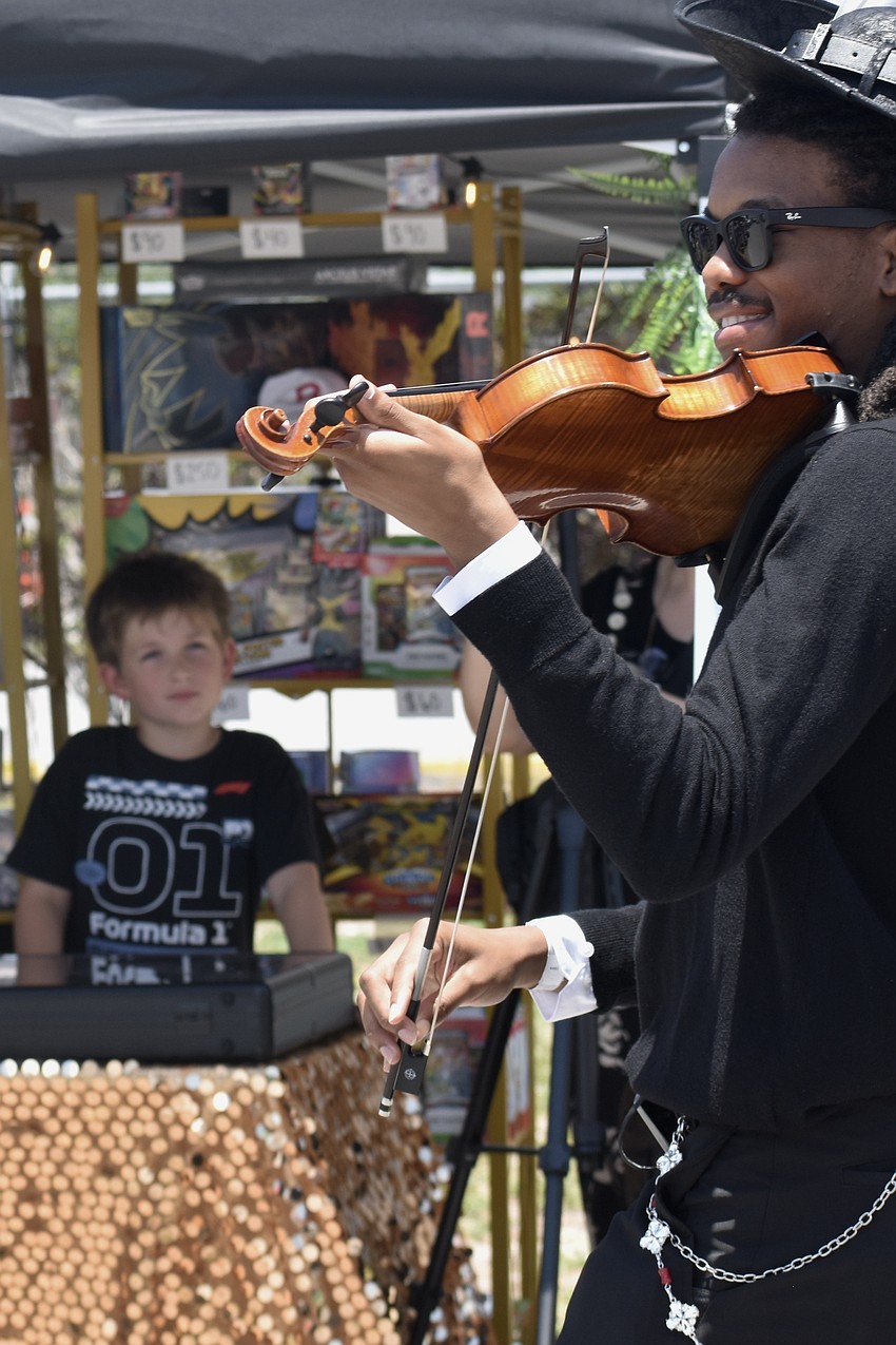 Silas Stacy, 7 watches from his family's Trade Guru Dealership table as Jonathan DeWitty makes the rounds, playing the violin and dressed as the character Brook from 