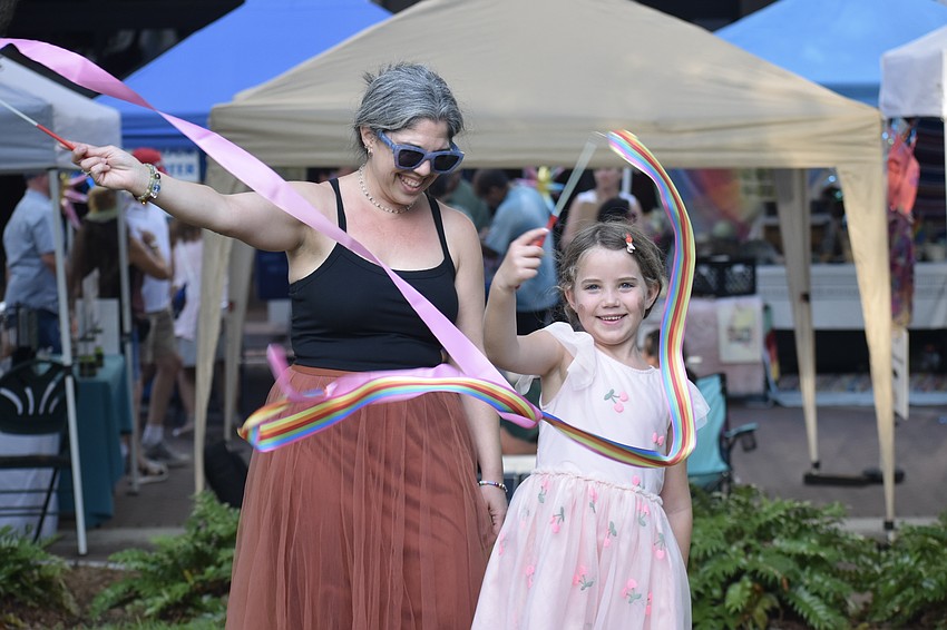 Amanda Dilliland and her daughter Yari Dilliland, 7, wave some ribbons on the park green.