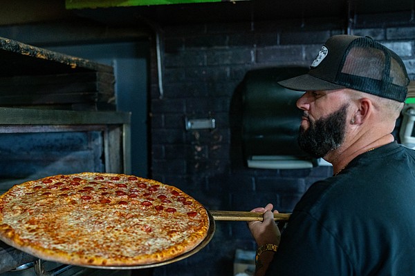 Costello’s Neighborhood Pizza owner Kenny Palin takes a pie out of the oven at the Longboat Key branch of Costello’s.