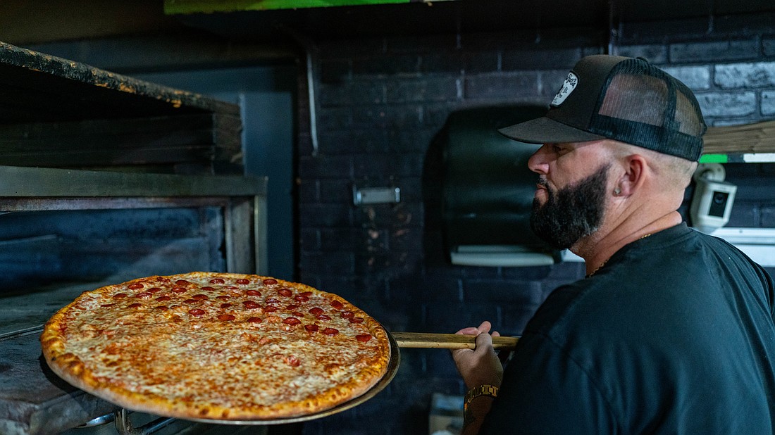 Costello’s Neighborhood Pizza owner Kenny Palin takes a pie out of the oven at the Longboat Key branch of Costello’s.