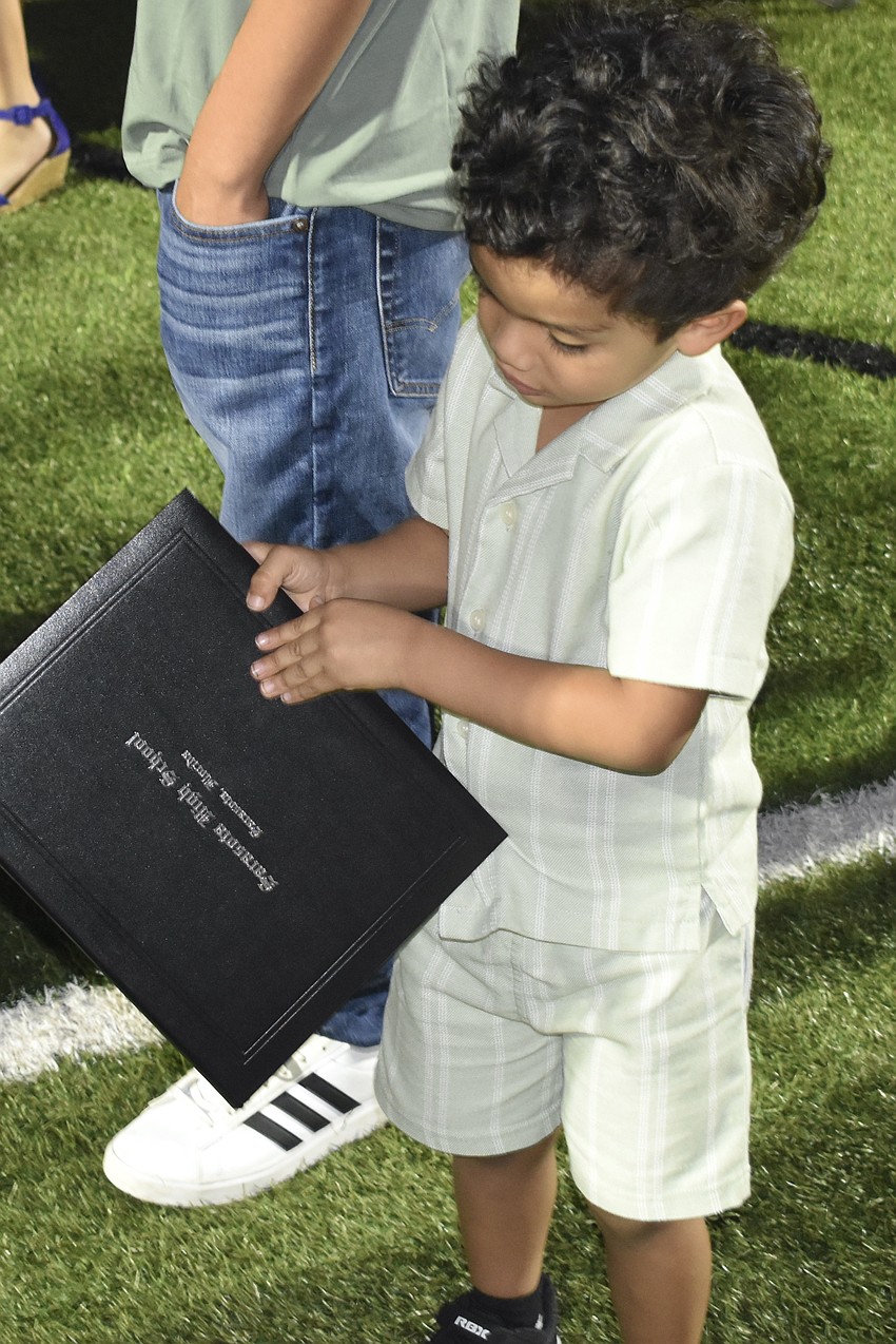 Jairus Hernandez, 3, looks at the diploma of his sister Genesis Hernandez.