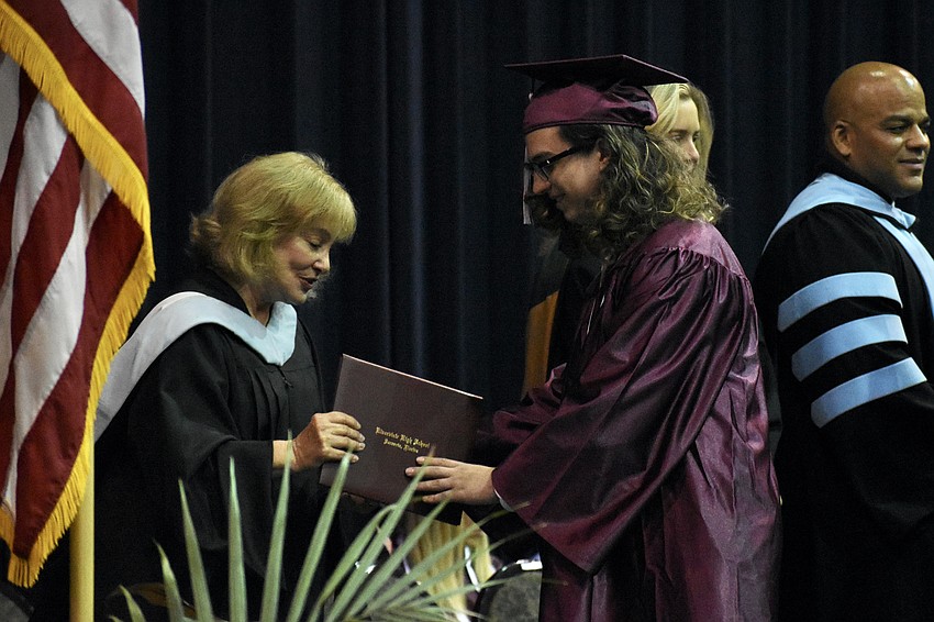 School board member Robyn Marinelli presents a diploma to Waylon Dunlap.