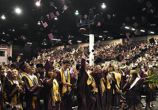 Students toss their caps as the status of graduation is conferred.