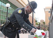 Florida Highway Patrol Trooper Michelson Fleurant places a rose on a plaque at the Manatee County Law Enforcement Memorial Service May 14 in Bradenton.