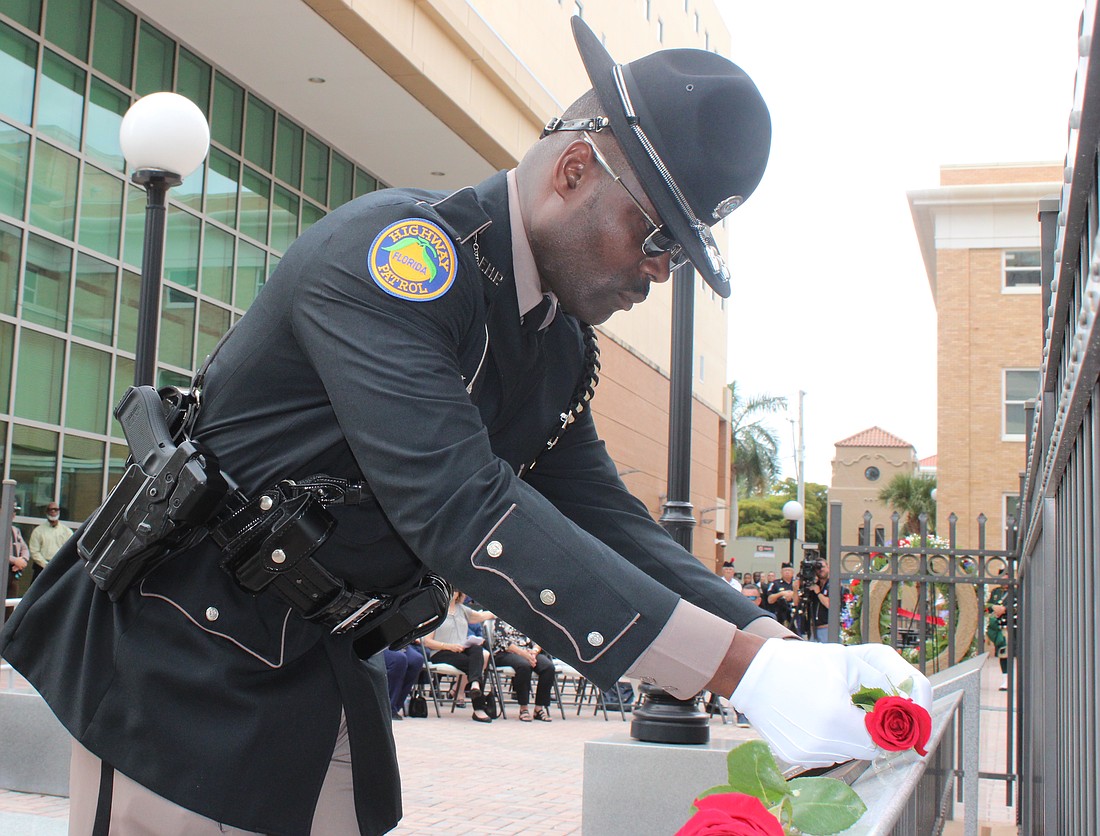 Florida Highway Patrol Trooper Michelson Fleurant places a rose on a plaque at the Manatee County Law Enforcement Memorial Service May 14 in Bradenton.