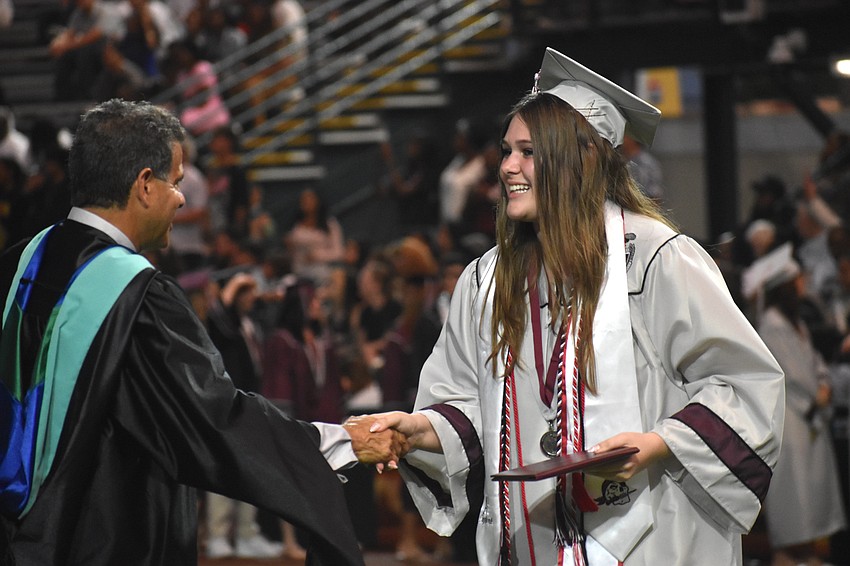 Matthew Nesser, athletic director at Braden River High School, shakes hands with graduate Kylie Mohamed.