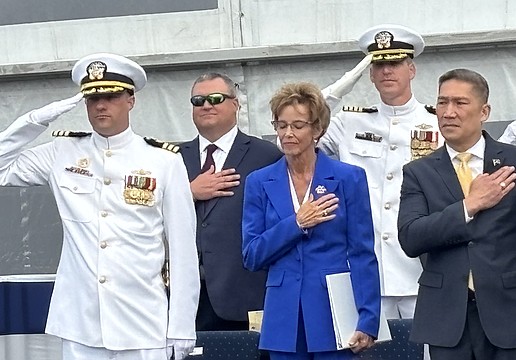 Robyn Modly, sponsor of the USS Cleveland, takes in the Navy band’s performance of the “Star Spangled Banner” aside Bruce Hallet, left, commander of the USS Cleveland, and Hung Cao, acting secretary of the Navy.