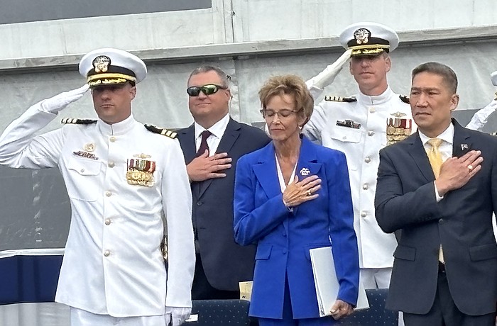 Robyn Modly, sponsor of the USS Cleveland, takes in the Navy band’s performance of the “Star Spangled Banner” aside Bruce Hallet, left, commander of the USS Cleveland, and Hung Cao, acting secretary of the Navy.