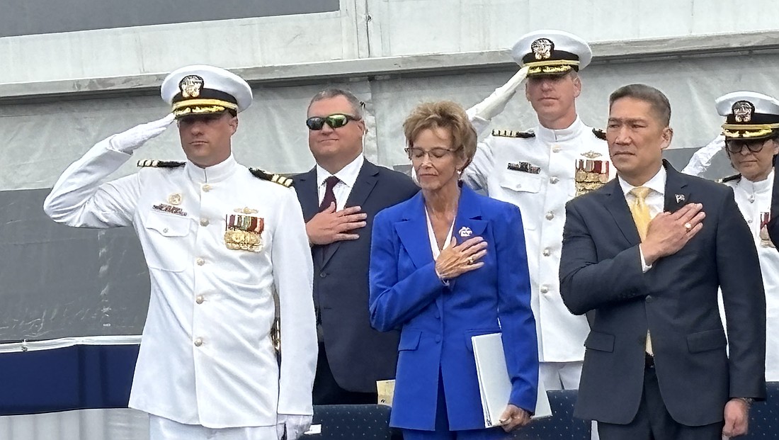 Robyn Modly, sponsor of the USS Cleveland, takes in the Navy band’s performance of the “Star Spangled Banner” aside Bruce Hallet, left, commander of the USS Cleveland, and Hung Cao, acting secretary of the Navy.
