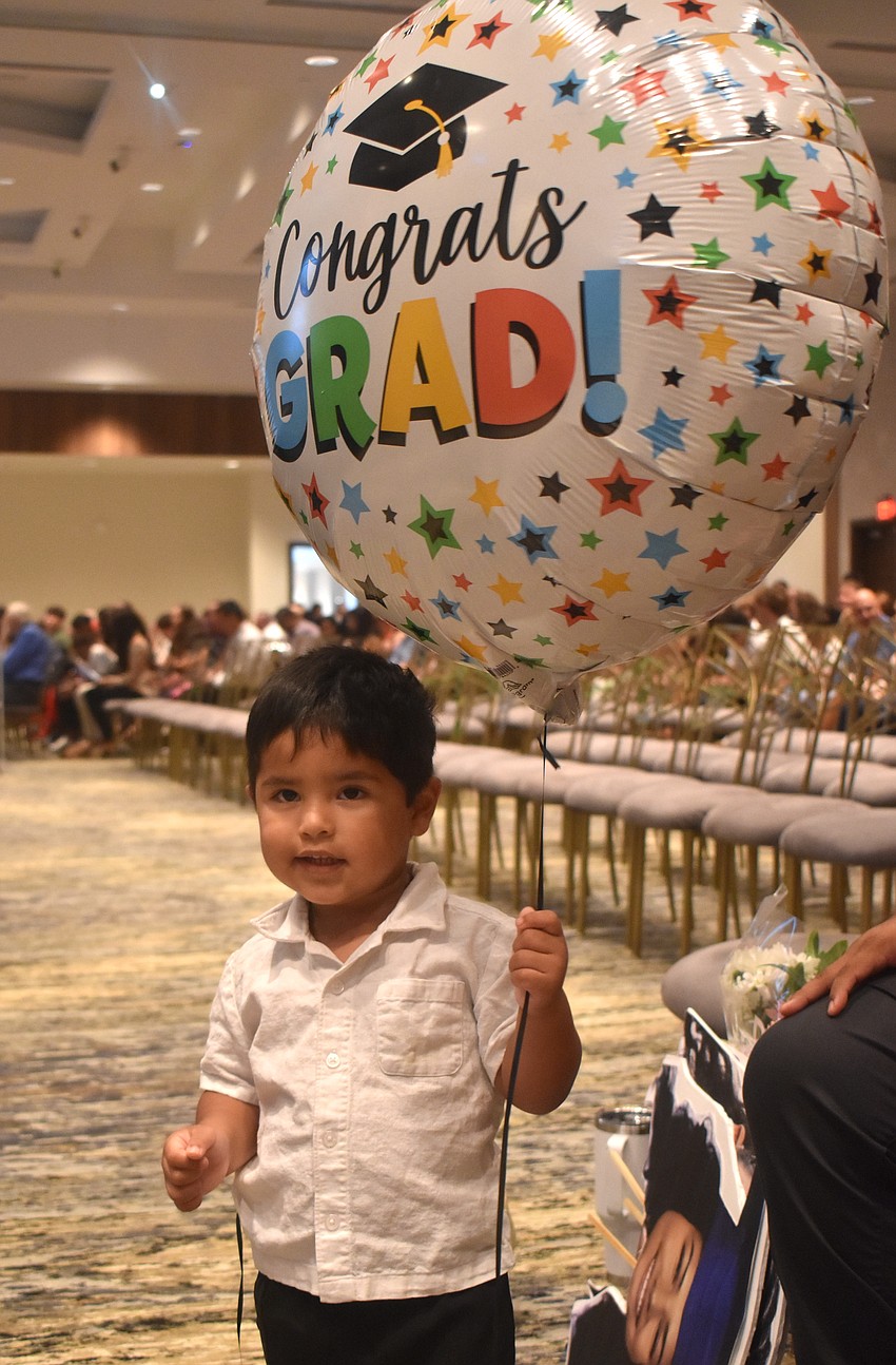 Marc Sacta, 2, is responsible for the oversized balloon until it can be given to graduate Kayla Moreira.