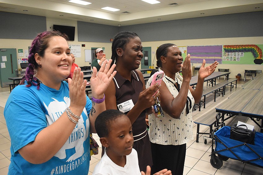 Teacher Amber Williams, and Noah Moise's nephew Dakari Douglas, sister Gallandy Moise and mother Ligardy Moise cheer him on as he receives the award.