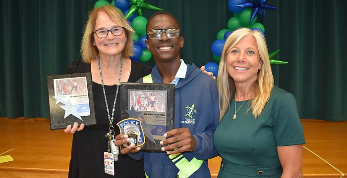 School safety patrol supervisor Justine Holcomb, Noah Moise and Principal Patti Folino stand together.