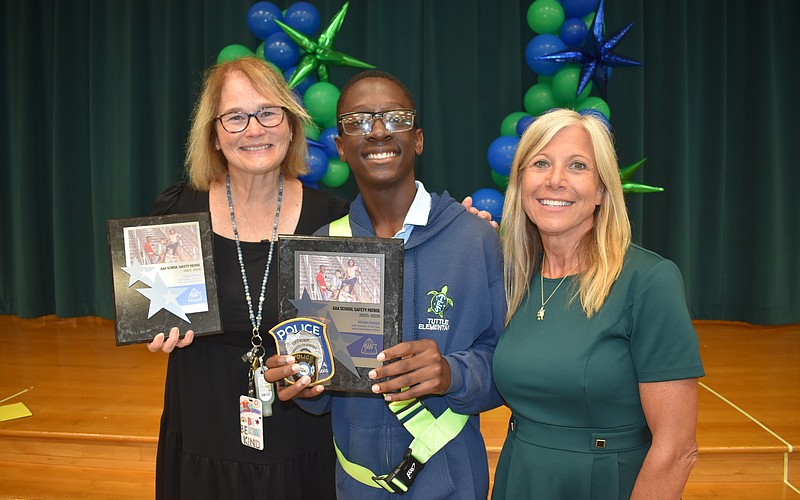School safety patrol supervisor Justine Holcomb, Noah Moise and Principal Patti Folino stand together.