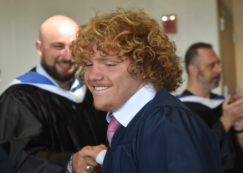As graduate Mays Montagna passes through various Out-of-Door Academy educators, he gives Assistant Football Coach Mike Zaloga a handshake.