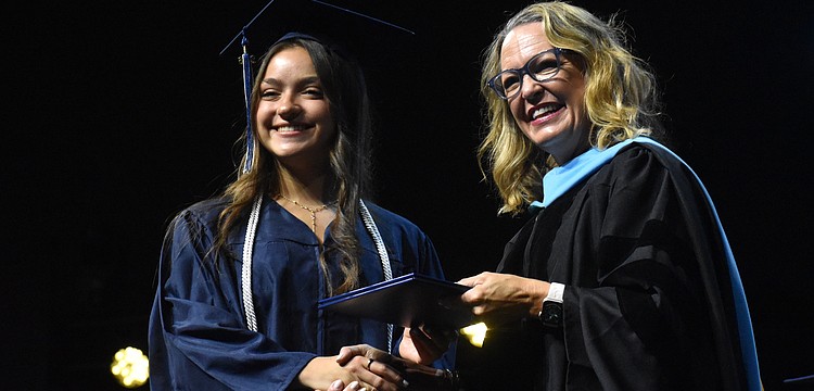 Oceane Visa, who says she has waited years to walk across the stage for graduation, is congratulated by Head of School Debra Otey.
