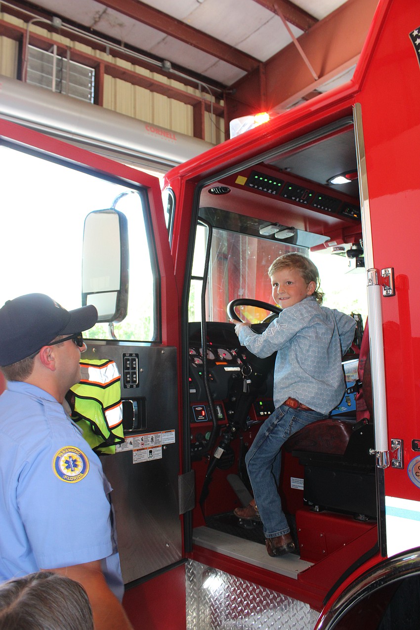 Firefighter James Bacigalupi watches as Harry Noordzy checks out a fire truck during his belated 5-year-old birthday visit.