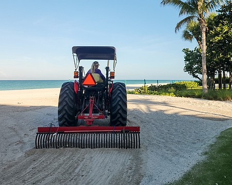 Angie Cupp uses a tractor and landscaping rake attachment to clean Longboat Key beaches of debris.
