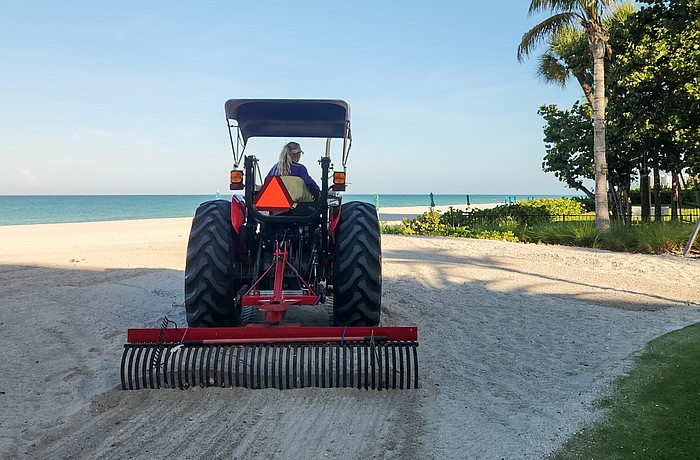 Angie Cupp uses a tractor and landscaping rake attachment to clean Longboat Key beaches of debris.