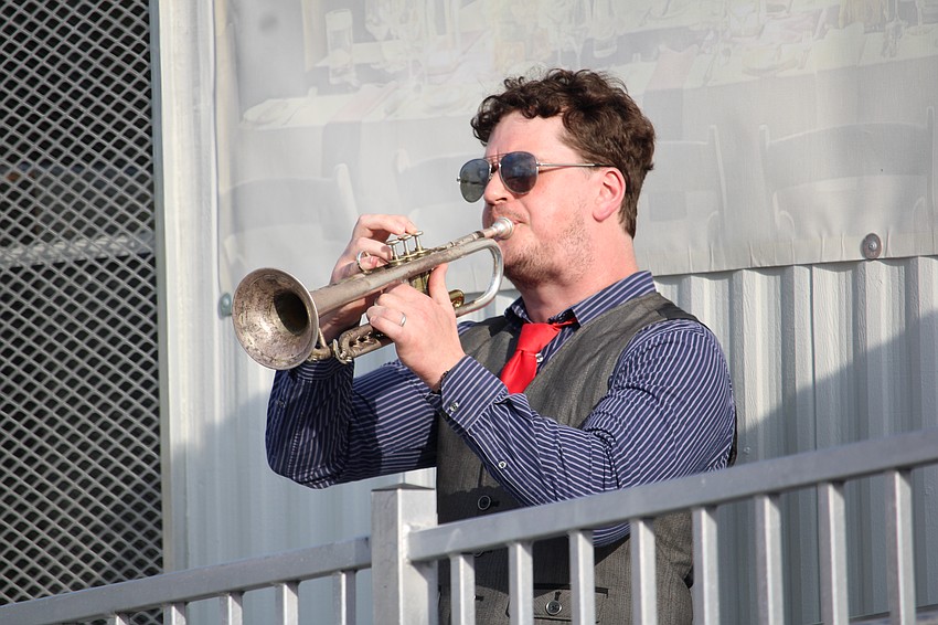 Kevin Celebi plays the trumpet while the American flag is raised.
