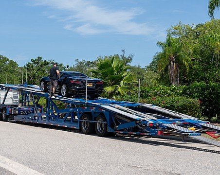 A car carrier operator unloads a Corvette on Bay Isles Road, the town of Longboat Key’s designated dropoff and pickup area for car carriers.