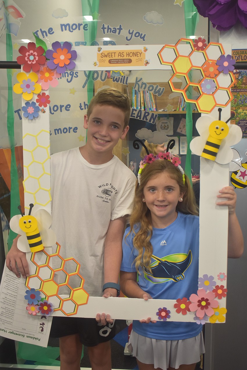 Lakewood Ranch's Connor Biegel, 12, and Reagan Biegel, 7, discover bee facts and details scattered throughout the children's section during the Summer Learning Program Kickoff Party.