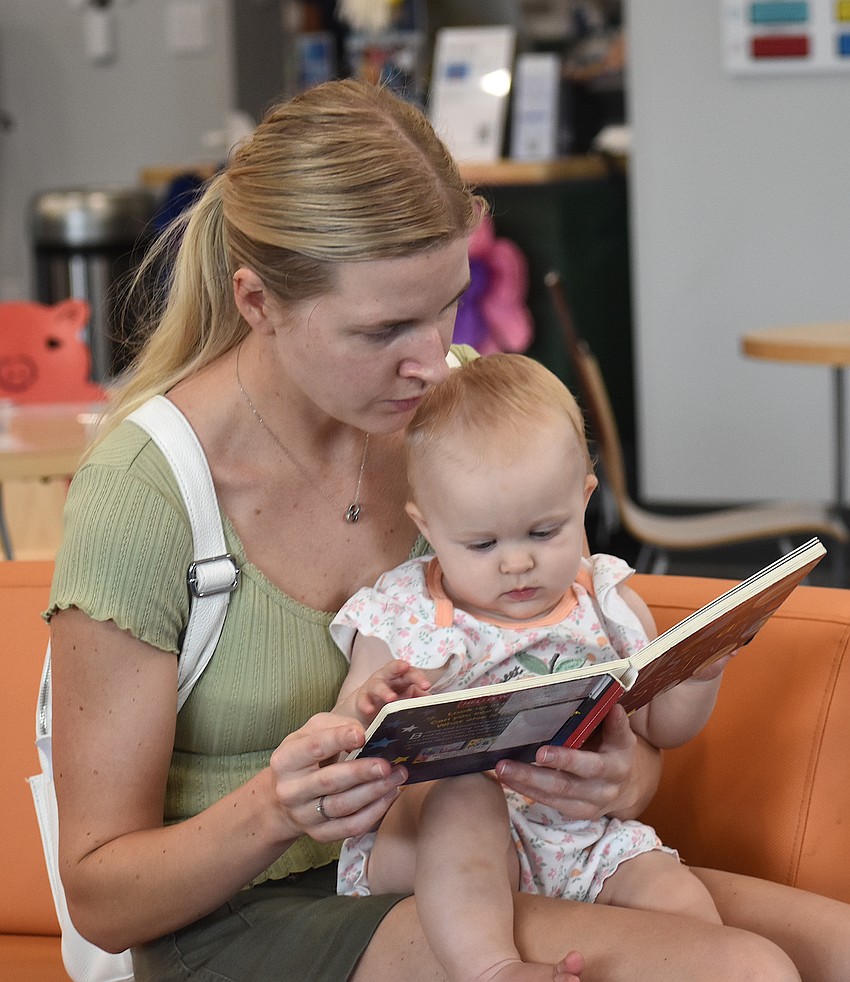 Lakewood Ranch's Sviatoslava Mazur reads a book to her daughter, 10-month-old Milana Lavrynovych, at the Lakewood Ranch Library during the Summer Learning Program Kickoff Party.