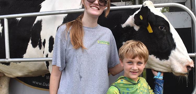 Gabrielle Finnegan, chapter president of the Lakewood Ranch High School Future Farmers of America, checks out Lucy the cow with 7-year-old camper Luca Bellantonio.