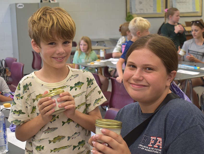 Lakewood Ranch's Teddy Kirsch, 8, and Tiffany Granville, a camp counselor 
and FFA member, are happy to make their own butter with cream donated by Dakin Dairy.