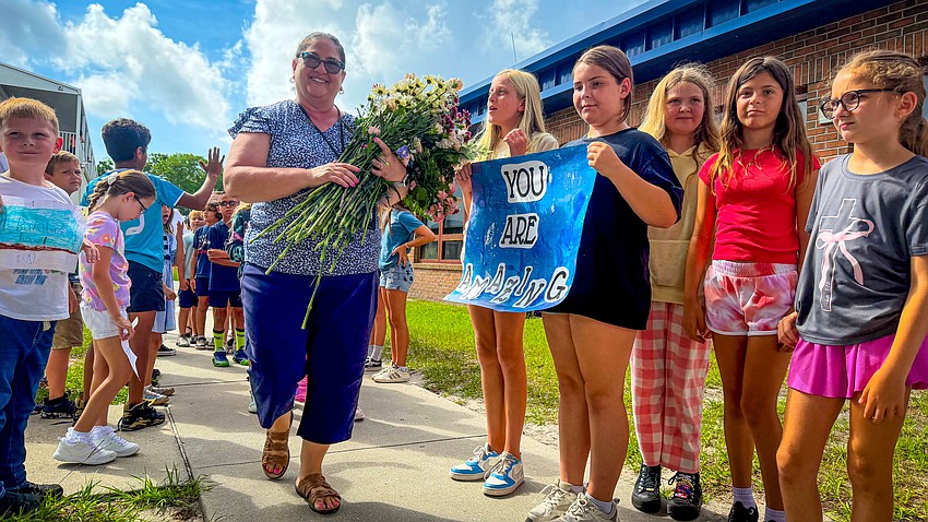 Students hold signs honoring Old Kings Elementary School teacher Nancy Allesee at her final call on May 27. Photo courtesy of Flagler Schools
