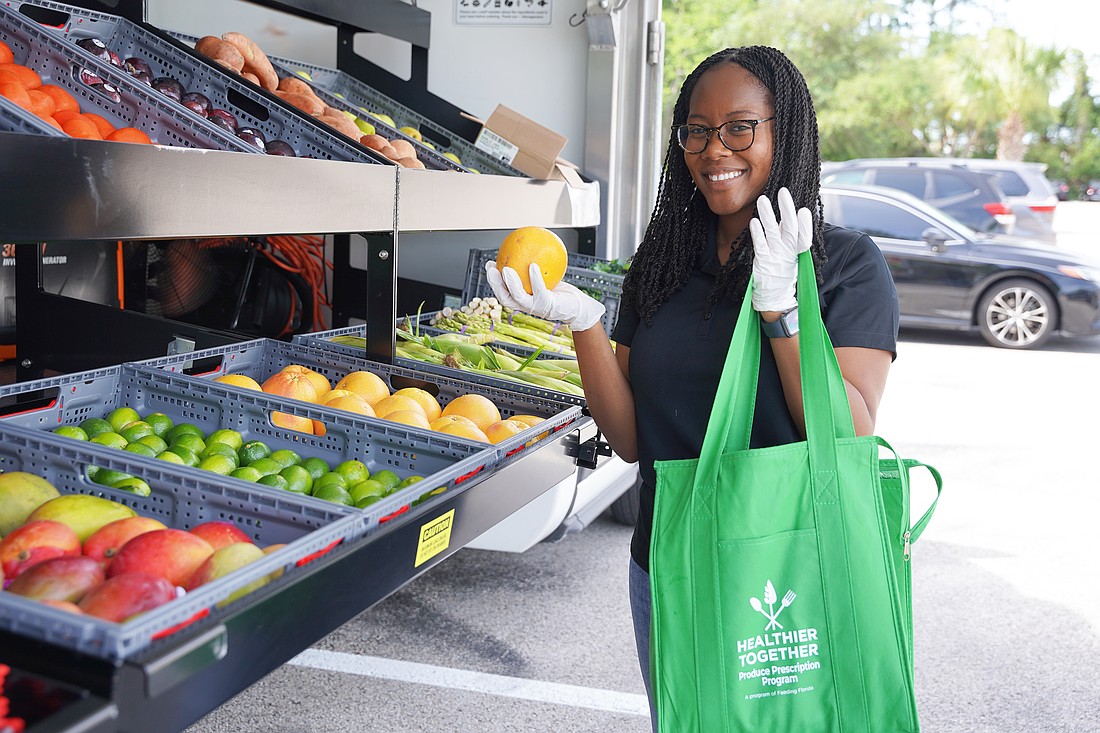 Ann-Aicha St. Cyr, health promotions manager at Second Harvest Food Bank of Central Florida, fills a produce prescription at the Mobile Farmers Market. Photo courtesy of Second Harvest Food Bank of Central Florida