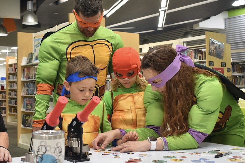 Stephen Cook, Emerson Cook, 6, Elliott Cook, 8 and Jennifer Cook create a set of buttons.