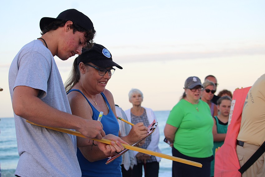 Brenda and Ben Jameson work side by side to jot down data collected about the turtle nest's position relative to the shoreline and the brush. Working to protect the turtles has become a project for the whole family, and while the pair was leading a Turtle Walk on Longboat Key, Brenda's other son, Caleb, was working further south to relocate nests ahead of planned beach renourishment work.