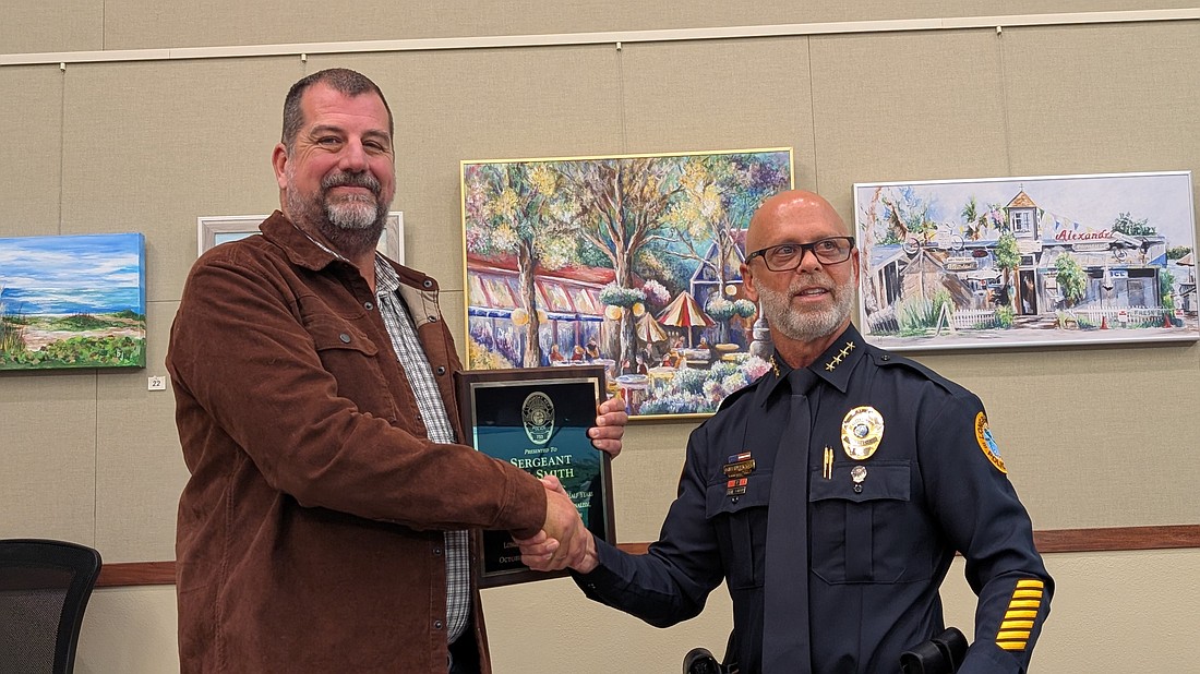 Longboat Key Police Chief Russ Mager (right) presents Lee Smith with a plaque recognizing his years with the police department at the June 1 Town Commission meeting. Smith retired from his position as sergeant on May 29.